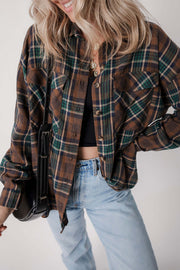 Oversized brown plaid button-up shacket with rolled sleeves paired with denim jeans and neutral top
