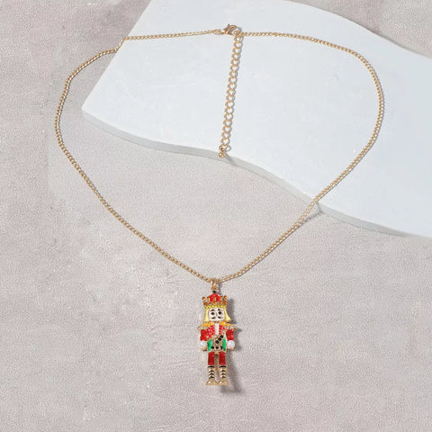 18K Gold Nutcracker Pendant Necklace on a marble surface, featuring a colorful Nutcracker charm and delicate gold chain.