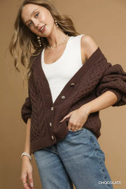 Model wearing a Pearl Button Cable Knit Cardigan in chocolate color, styled with a white tank top and relaxed jeans.