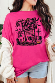 Bookstore Skeleton Halloween Graphic Heavy Cotton Tee in pink with spooky skeleton design and bookstore sign.
