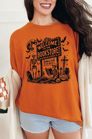 Bookstore Skeleton Halloween Graphic Heavy Cotton Tee featuring a spooky design on a vibrant orange shirt.
