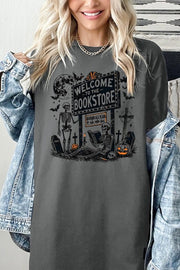 Bookstore Skeleton Halloween Graphic Heavy Cotton Tee featuring skeletons and pumpkins in a playful design.