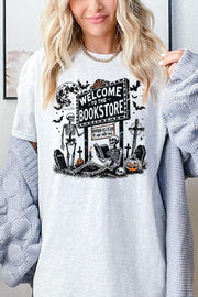 Bookstore Skeleton Halloween Graphic Heavy Cotton Tee featuring playful skeleton design and welcoming sign.