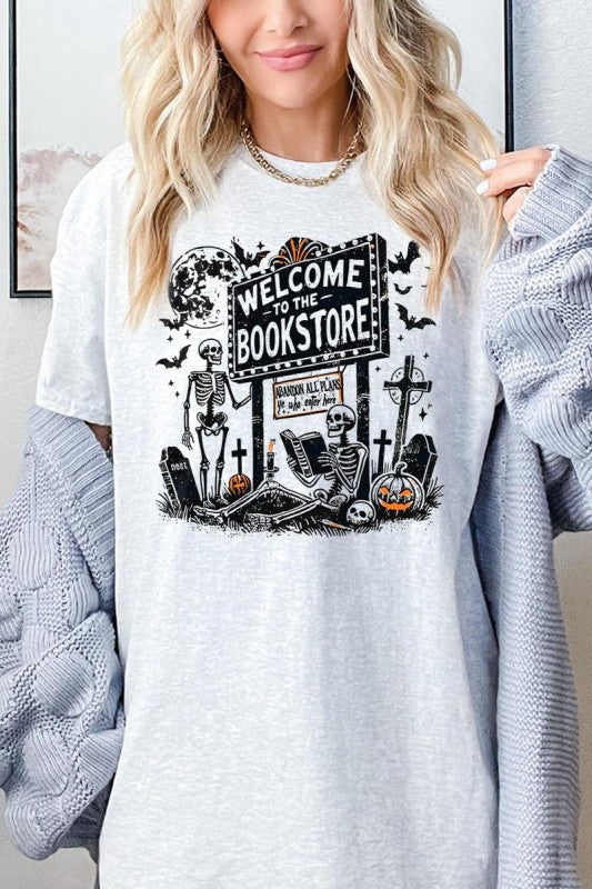 Bookstore Skeleton Halloween Graphic Heavy Cotton Tee featuring playful skeleton design and welcoming sign.