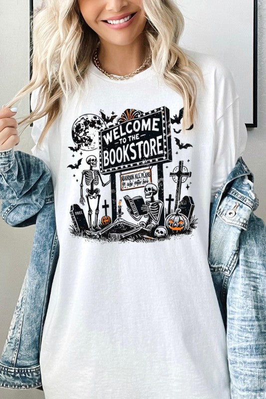 Bookstore Skeleton Halloween Graphic Heavy Cotton Tee featuring playful skeletons with bookstore sign and Halloween motifs.