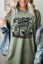 Bookstore Skeleton Halloween Graphic Heavy Cotton Tee worn by a smiling woman, featuring a spooky bookstore graphic.