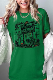 Bookstore Skeleton Halloween Graphic Heavy Cotton Tee featuring playful skeleton design on a green background.