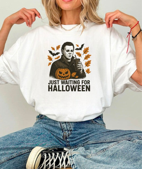 Model wearing Just Waiting Halloween Graphic Tee with spooky graphic and autumn leaves.