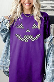 Checker Pumpkin Face Graphic Heavy Cotton Tee worn by a woman, featuring a playful checker pumpkin face design on a purple shirt.
