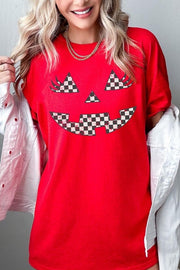 Checker Pumpkin Face Graphic Heavy Cotton Tee worn by a woman, featuring a checker pumpkin face design on a red background.