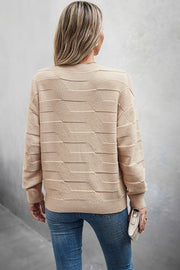 Back view of a woman wearing a Classic Round Neck Loose Knit Sweater in beige, styled with blue jeans.