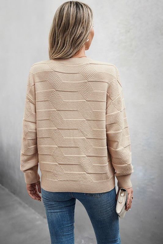 Back view of a woman wearing a Classic Round Neck Loose Knit Sweater in beige, styled with blue jeans.