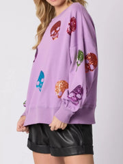 Halloween Colorful Skull Sequin Oversized Sweatshirt featuring vibrant sequin skulls on a purple background.