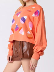 Halloween Candy Sequin Long-Sleeve Sweatshirt worn by a model with colorful candy designs.