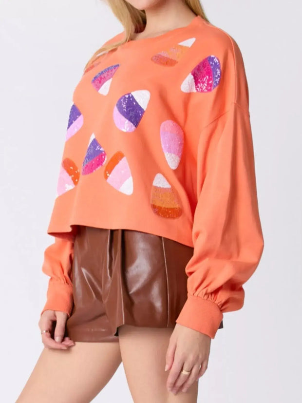 Halloween Candy Sequin Long-Sleeve Sweatshirt worn by a model with colorful candy designs.
