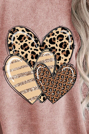 Close up of Heart Ribbed Round Neck Sweatshirt worn by a model, featuring leopard print hearts with a cozy pink hue.