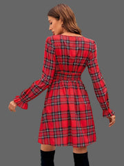 Back view of a woman wearing a red Plaid Holiday Mini Dress – smocked & ruffled, showcasing the stylish design.