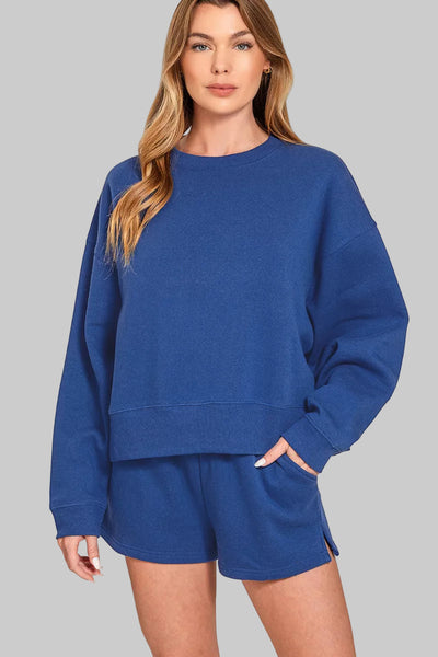 Model wearing the Zenana Fleece Round Neck Sweatshirt & Shorts Set in blue, showcasing comfort and casual style.