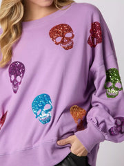 Halloween Colorful Skull Sequin Oversized Sweatshirt featuring vibrant sequin skulls on a lavender background.