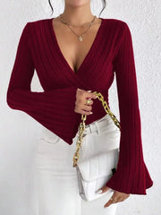 Model wearing a Ribbed Flare Sleeve Top in burgundy with flared sleeves and a v-neck, paired with white jeans.