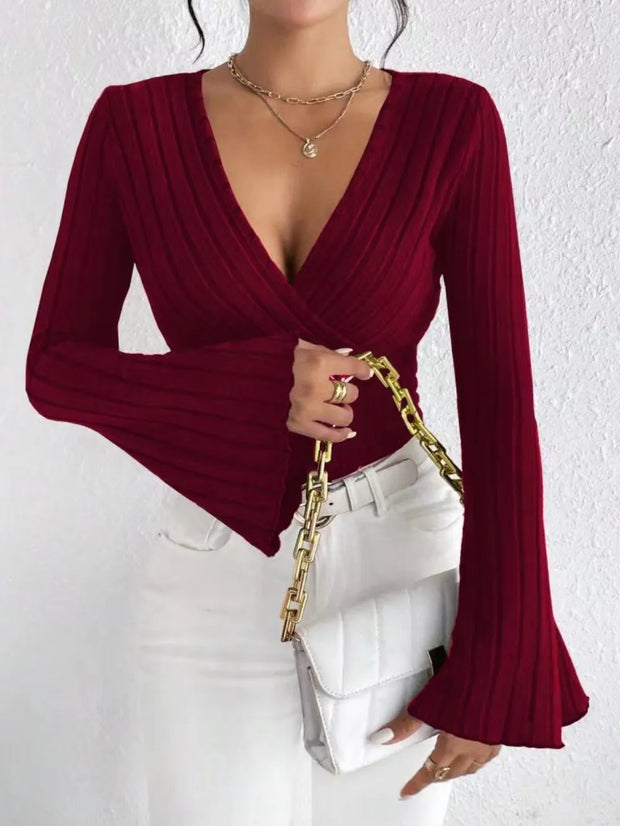 Model wearing a Ribbed Flare Sleeve Top in burgundy with flared sleeves and a v-neck, paired with white jeans.
