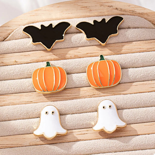 3-Pair Halloween Stud Earring Set featuring bat, pumpkin, and ghost designs on a wooden background.