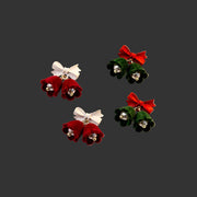 Velvet Bell Earrings with Bow displayed on a jewelry stand with holiday decorations in the background.
