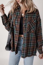 Model styling brown plaid button-up shacket open over brown top and denim jeans