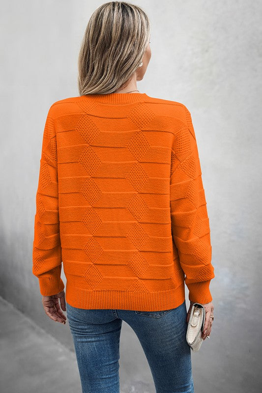 Back view of a woman wearing a Classic Round Neck Loose Knit Sweater in orange with a textured pattern.