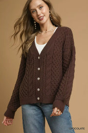 Model wearing a Pearl Button Cable Knit Cardigan in chocolate color, featuring pearl buttons and classic cable knit texture.