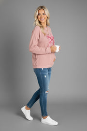 Side view of a model wearing Bow Graphic Round Neck Long Sleeve Sweatshirt with a pink bow graphic, paired with distressed jeans.