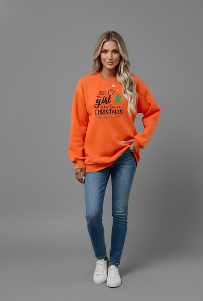 Woman in an orange Letter Graphic Round Neck Sweatshirt with festive Christmas design and blue jeans.
