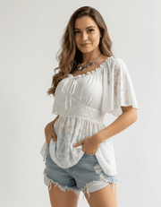 Model wearing Floral Tie-Front Smocked Back Flutter Sleeve Blouse  with tie front and frilled details — soft, romantic top styled with denim shorts