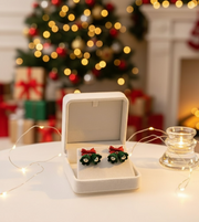 Velvet Bell Earrings with Bow displayed on a jewelry stand with holiday decorations in the background.