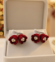Velvet Bell Earrings with Bow displayed on a jewelry stand with holiday decorations in the background.
