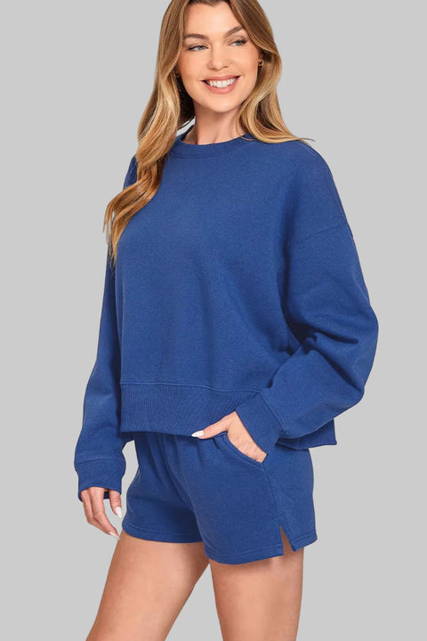 Zenana Fleece Round Neck Sweatshirt & Shorts Set displayed on a smiling model in blue.