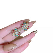 18K Gold Snowflake Stud Earrings featuring colorful rhinestones and intricate snowflake design held in hand.