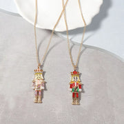 18K Gold Nutcracker Pendant Necklace displayed on a plate, featuring two colorful Nutcracker charms.