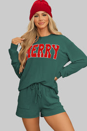 Woman wearing the Evergreen MERRY Corded Lounge Set with a festive red beanie in front of a Christmas tree.