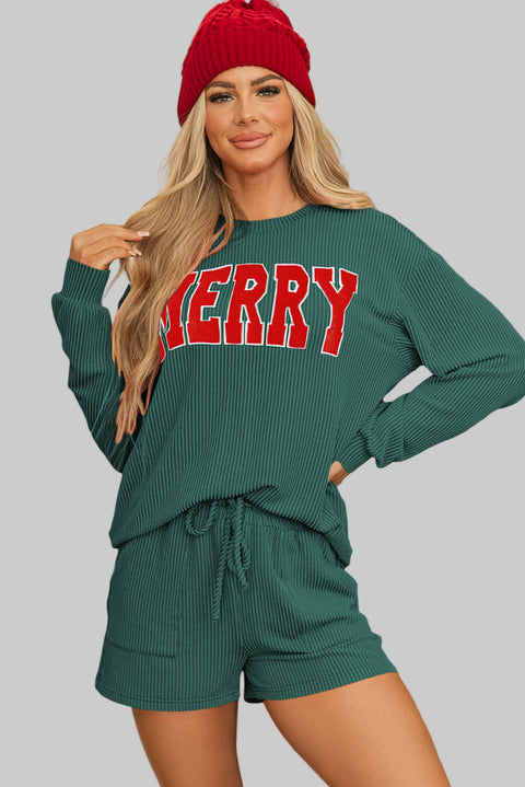 Woman wearing the Evergreen MERRY Corded Lounge Set with a festive red beanie in front of a Christmas tree.
