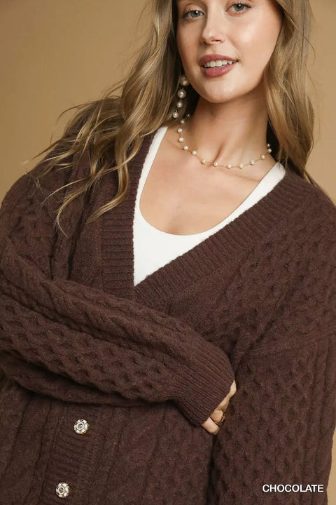 Model showcasing the Pearl Button Cable Knit Cardigan in chocolate, featuring pearl buttons and a cable knit design.