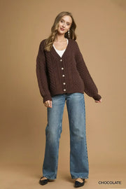 Model wearing a Pearl Button Cable Knit Cardigan with pearl buttons and relaxed fit, styled with denim jeans.