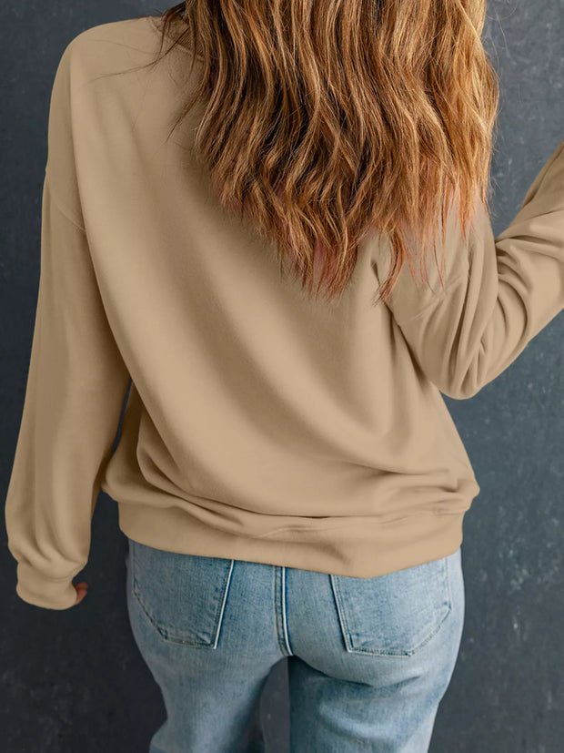 Woman wearing a relaxed drop-shoulder sweatshirt, showcasing the back view, styled with light denim jeans.
