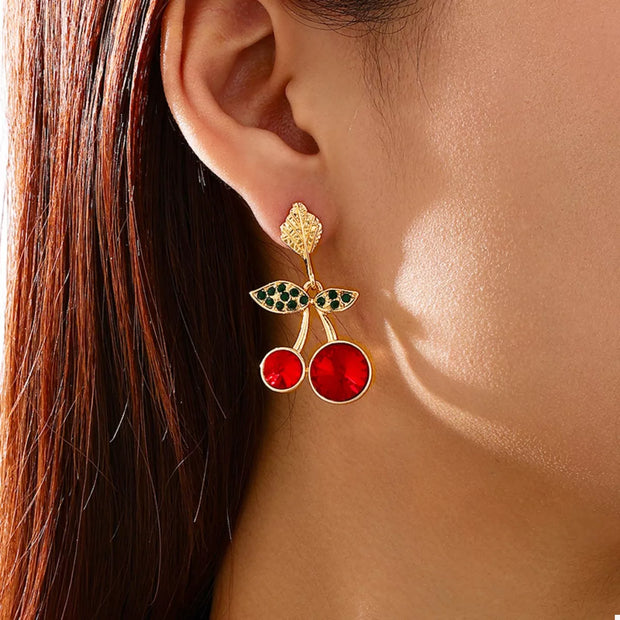 18K Gold-Plated Cherry Drop Earrings – Playful Statement Jewelry worn by a woman, featuring glossy red cherries and green leaves.
