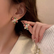 18K Gold Snowflake Stud Earrings showcasing winter sparkle with colorful rhinestones on a model's ear.