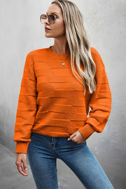 Woman wearing a Classic Round Neck Loose Knit Sweater in orange, styled with jeans and sunglasses.