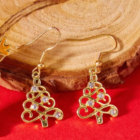 18K Gold Christmas Tree Earrings with rhinestones on a wooden surface.