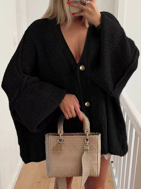 Buttoned Blouse in black with oversized sleeves and buttons, styled with a beige handbag.