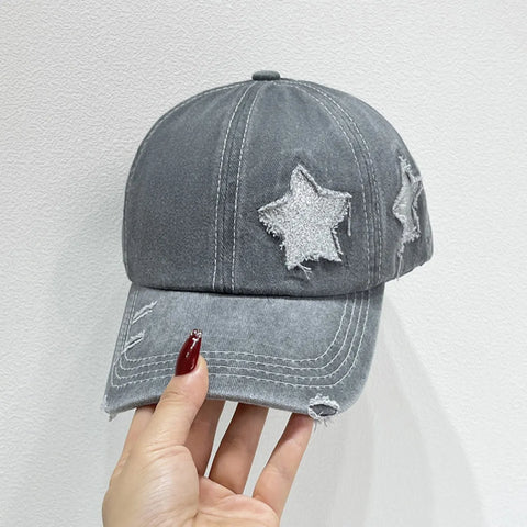 Hand holding a Star Embroidered Baseball Cap with distressed star stitching in gray color.